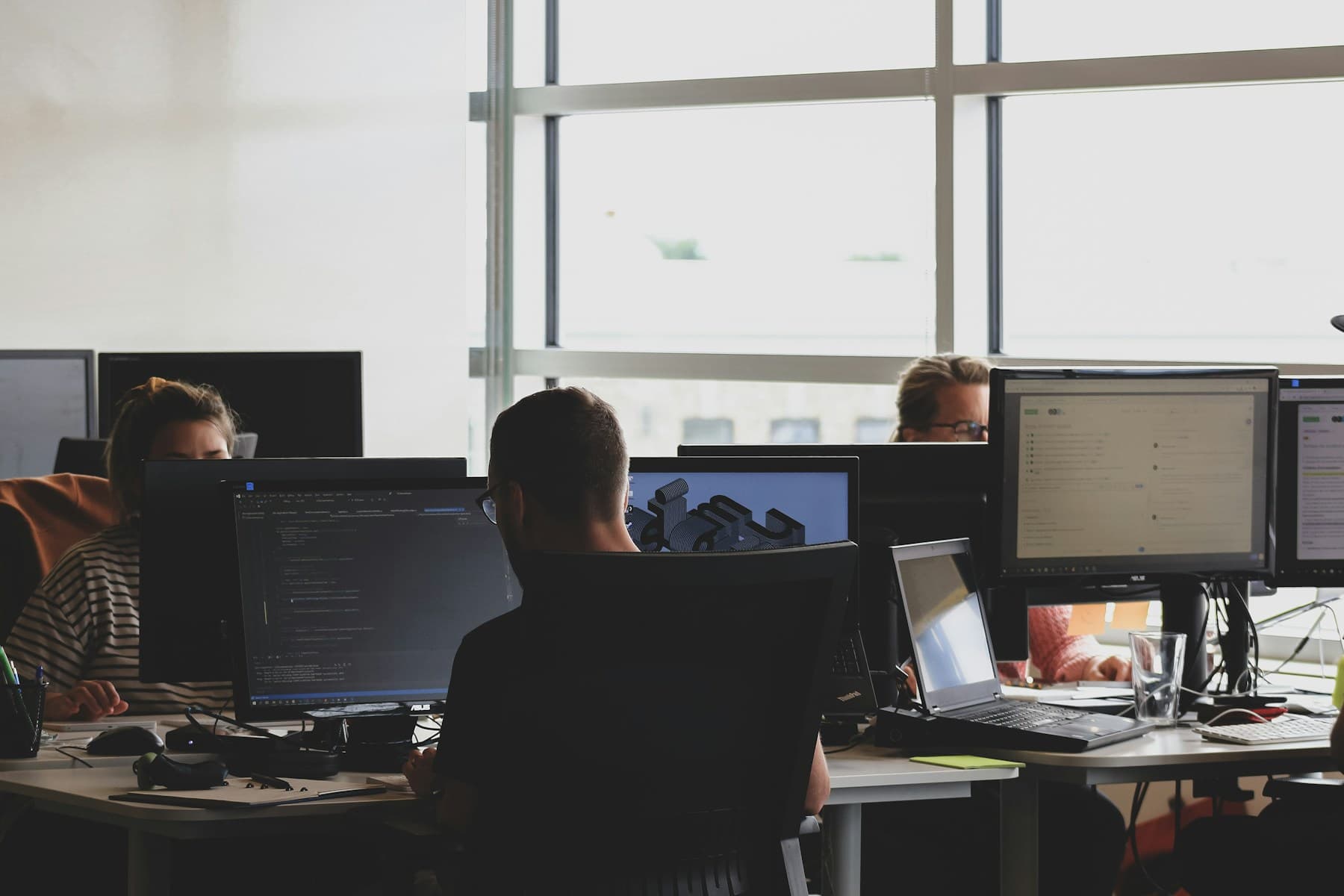 Persone al lavoro davanti a postazioni di sviluppo software